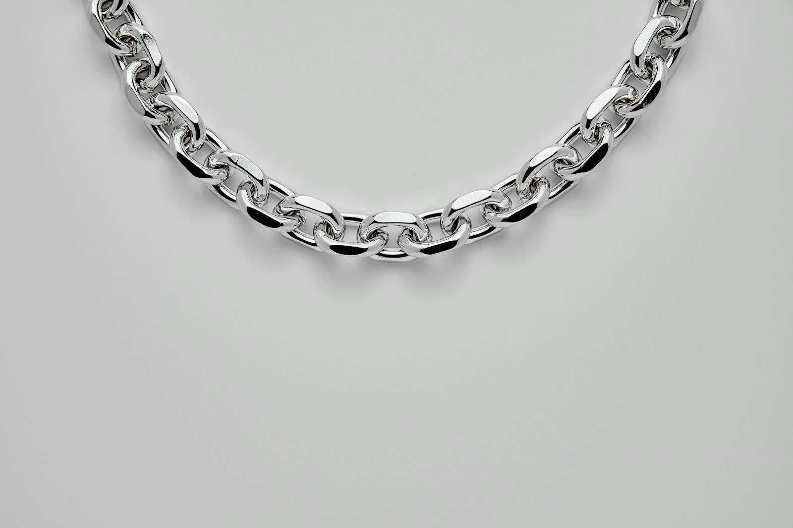 silver chain link bracelet on white surface